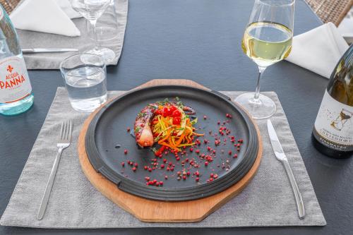 a plate of food on a table with a bottle of wine at Ammon Zeus Luxury Beach Hotel in Kallithea Halkidikis