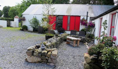 a garden with a bench in front of a building at Stone Wall Cottage in Castlewellan