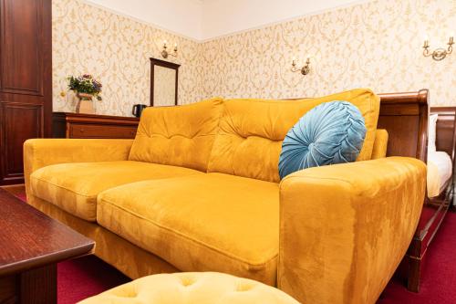 a living room with a yellow couch with a blue pillow at The Atholl Palace in Pitlochry