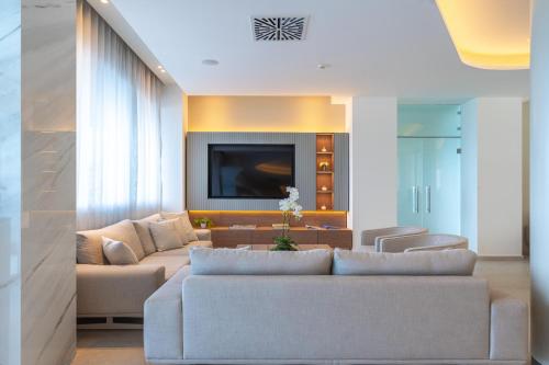 a living room with a couch and a tv at Ammon Zeus Luxury Beach Hotel in Kallithea Halkidikis