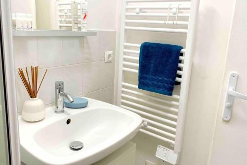 - une salle de bains blanche pourvue d'un lavabo et d'une serviette bleue dans l'établissement Spacieux studio - Au pied de la gare Cergy-le-Haut, à Cergy