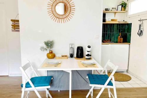 une cuisine avec une table blanche et deux chaises bleues dans l'établissement Spacieux studio - Au pied de la gare Cergy-le-Haut, à Cergy
