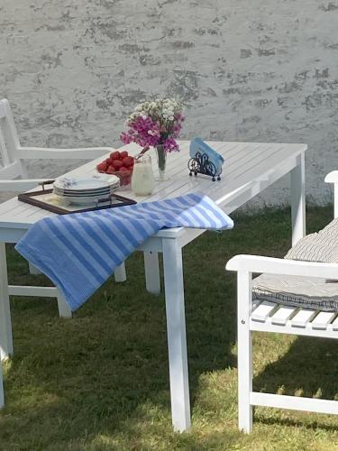 a white picnic table with flowers and fruit on it at Lækkert feriehus ved Lønstrup in Hjørring