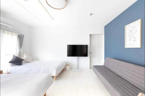 a bedroom with two beds and a tv on the wall at MUJIroomTaisyoOsaka in Osaka