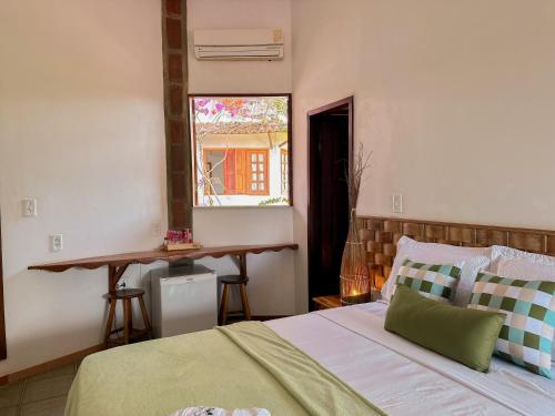 a bedroom with a bed and a window and a table at Pousada Morada do Sol in Jericoacoara