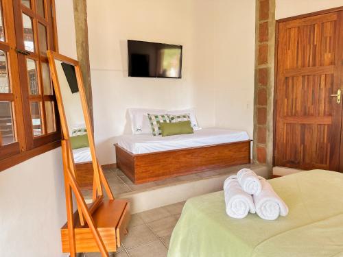 a bedroom with two beds and a television and a door at Pousada Morada do Sol in Jericoacoara
