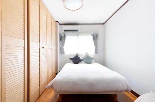 a bedroom with a bed with white sheets and a window at MUJIroomTaisyoOsaka in Osaka