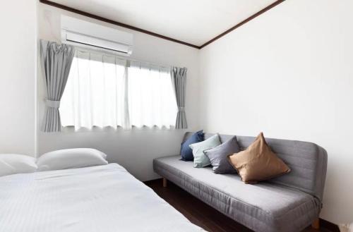 a bedroom with a couch and a window at MUJIroomTaisyoOsaka in Osaka