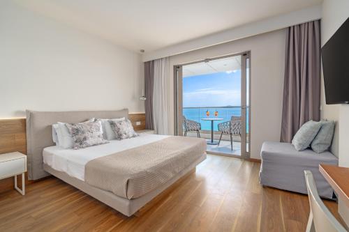 a bedroom with a bed and a view of the ocean at Ammon Zeus Luxury Beach Hotel in Kallithea Halkidikis