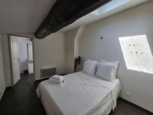 une chambre avec un lit avec des draps blancs et une fenêtre dans l'établissement Le Duplex du marin nîmois - Une Nuit à Nîmes, à Nîmes