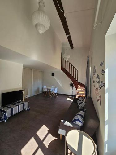 un salon avec un canapé et un escalier dans l'établissement Le Duplex du marin nîmois - Une Nuit à Nîmes, à Nîmes