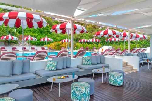 a pool with tables and chairs and umbrellas at Ammon Zeus Luxury Beach Hotel in Kallithea Halkidikis