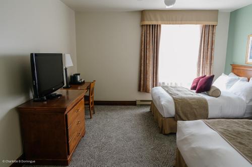 a hotel room with two beds and a flat screen tv at Hotel Tadoussac in Tadoussac