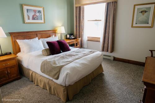 a hotel room with a large bed with purple pillows at Hotel Tadoussac in Tadoussac