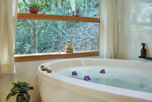 une baignoire dans une salle de bain avec une fenêtre dans l'établissement Chalé Ametista com ofurô e lareira, Santo Antônio do Pinhal, à Santo Antônio do Pinhal