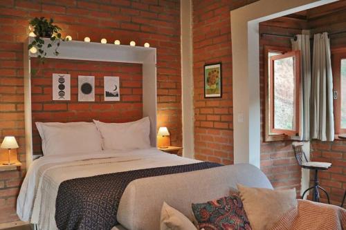 une chambre avec un lit et un mur de briques dans l'établissement Chalé Ametista com ofurô e lareira, Santo Antônio do Pinhal, à Santo Antônio do Pinhal