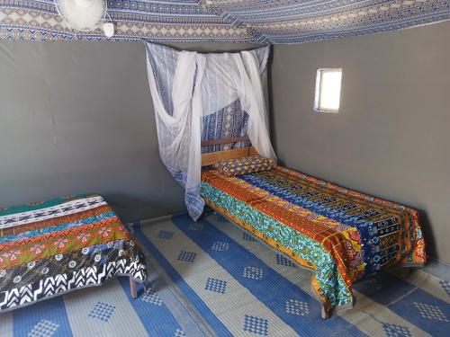a bedroom with two beds in a room with a ceiling at "Par 4 Chemins" - Atypical stopover in Nouakchott