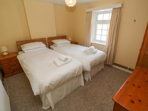deux lits jumeaux dans une chambre avec fenêtre dans l'établissement Brick Cottage, à Helston