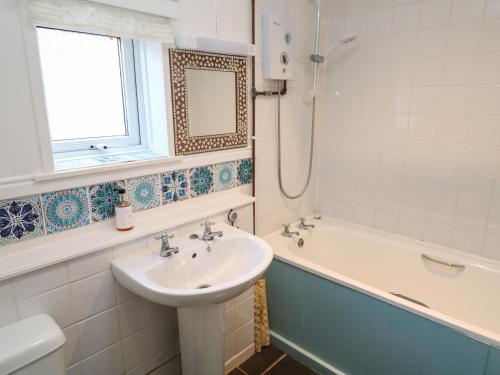une salle de bain blanche avec un lavabo et une baignoire dans l'établissement Brick Cottage, à Helston