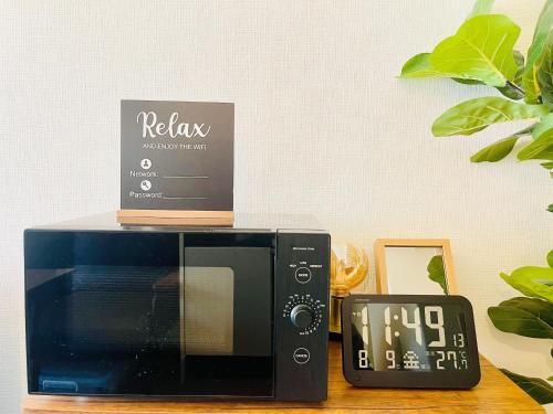 a microwave sitting on a table next to a clock at Alo BnB 12 - Game Universe - Easy Access to Shibuya - New ! in Tokyo