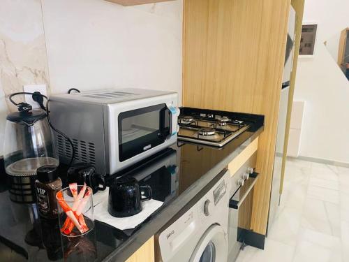 a small kitchen with a microwave and a stove at Studio cosy in Nouaceur