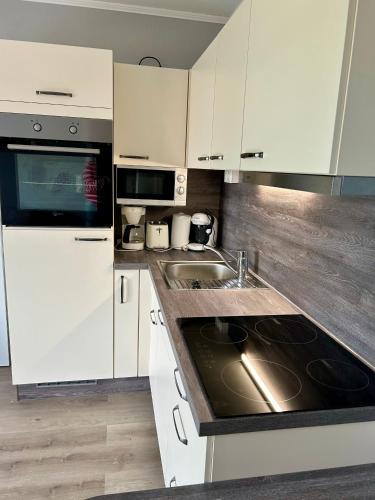 a kitchen with white cabinets and a sink at Friesenhof in Friedrichskoog