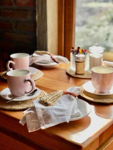 a wooden table with two cups and plates on it at Cabañas Puente Negro in Puente Negro