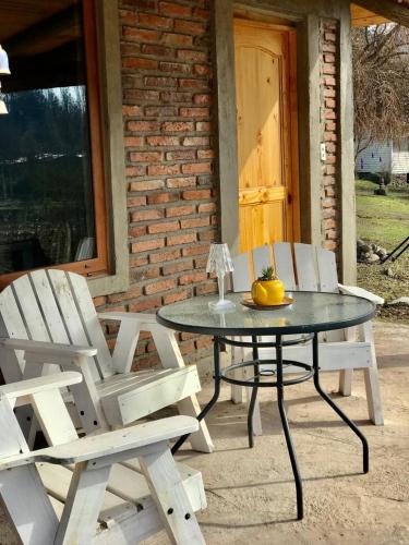 a table with two white chairs and a table with a fruit on it at Cabañas Puente Negro in Puente Negro