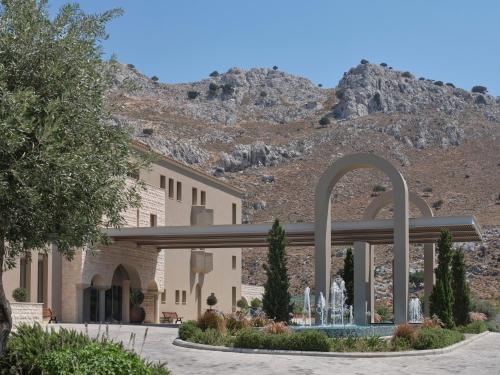 a building with a fountain in front of a mountain at Atlantica Aegean Park in Kolimbia