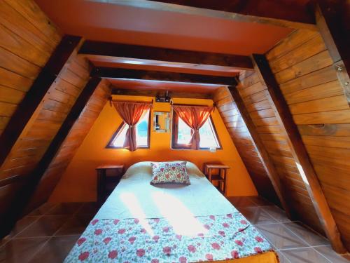 een kleine slaapkamer met een bed op zolder bij Alentue in Dina Huapi