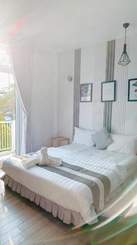 a large white bed in a room with a window at Sele House in Ha Tien