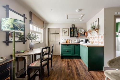 a kitchen with green cabinets and a table with chairs at Stunning Private en-suite studio in Cobham in Cobham