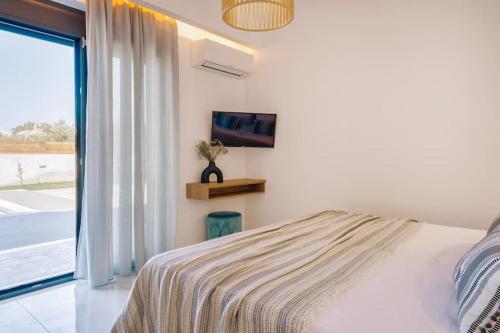 a bedroom with a bed and a tv on the wall at Xenia, Relaxing Pool Villa in Gaïtánion