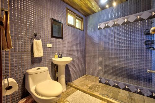 a blue tiled bathroom with a toilet and a sink at Luxury Villa Panorama Verde Pool House in Punta Uva