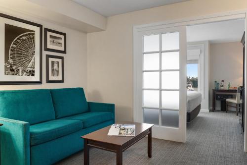 a living room with a blue couch and a bed at Peacock Suites in Anaheim