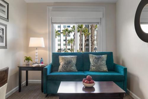 a living room with a blue couch and a table at Peacock Suites in Anaheim