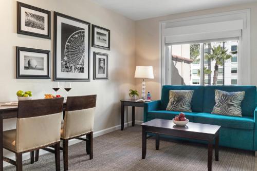 a living room with a blue couch and a table at Peacock Suites in Anaheim