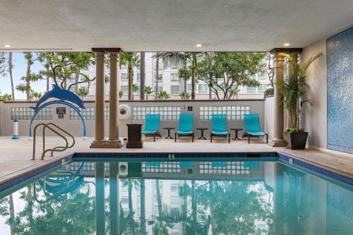 a swimming pool with blue chairs next to a building at Peacock Suites in Anaheim