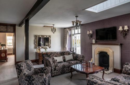 a living room with a couch and a fireplace at Stanbrook Abbey Hotel, Worcester in Worcester