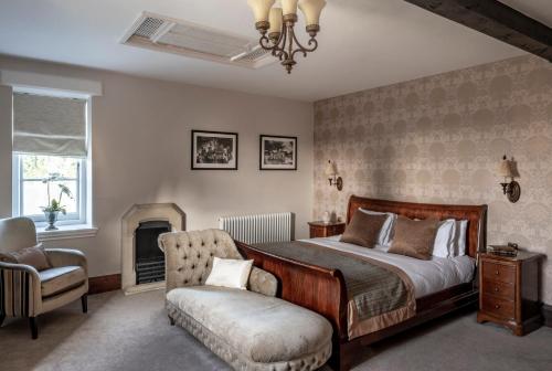 a bedroom with a bed and a chair and a fireplace at Stanbrook Abbey Hotel, Worcester in Worcester