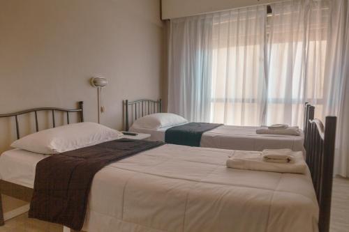 a bedroom with two beds and a window at Rayentray Hostal in Puerto Madryn