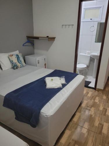 a bedroom with a bed with a blue blanket and a bathroom at Pousada sol e mar in Serra