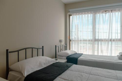 a bedroom with two beds and a window with a view at Rayentray Hostal in Puerto Madryn