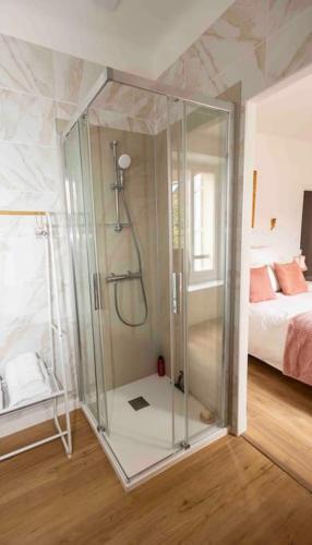 - une douche en verre dans une chambre avec un lit dans l'établissement Le Repaire, à Montigny-le-Gannelon