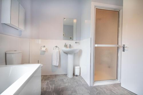 een witte badkamer met een wastafel en een douche bij Sunnyhill Cottage in North Erradale