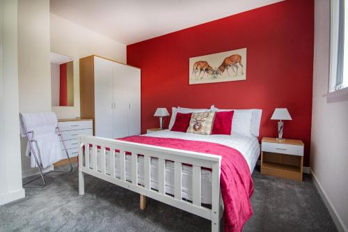 een slaapkamer met rode muren en een wit bed bij Sunnyhill Cottage in North Erradale