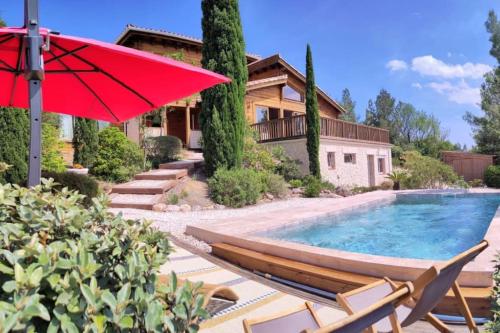 une maison avec une piscine et un parasol rouge dans l'établissement Les cigales magnifique maison en bois avec piscine, à Portel-des-Corbières