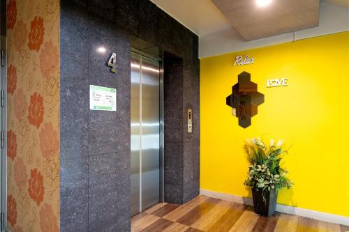 an elevator lobby with a yellow wall and a vase of flowers at P-Park Hotel Bangkok in Bangkok