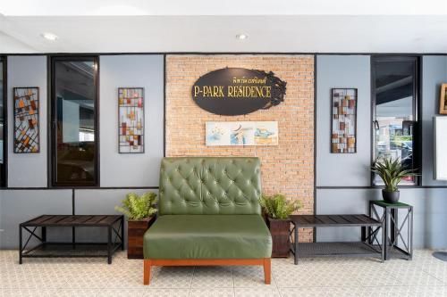 a waiting room with a green chair in front of a brick wall at P-Park Hotel Bangkok in Bangkok
