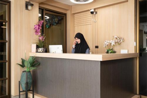 a woman talking on a cell phone at a counter at P-Park Hotel Bangkok in Bangkok